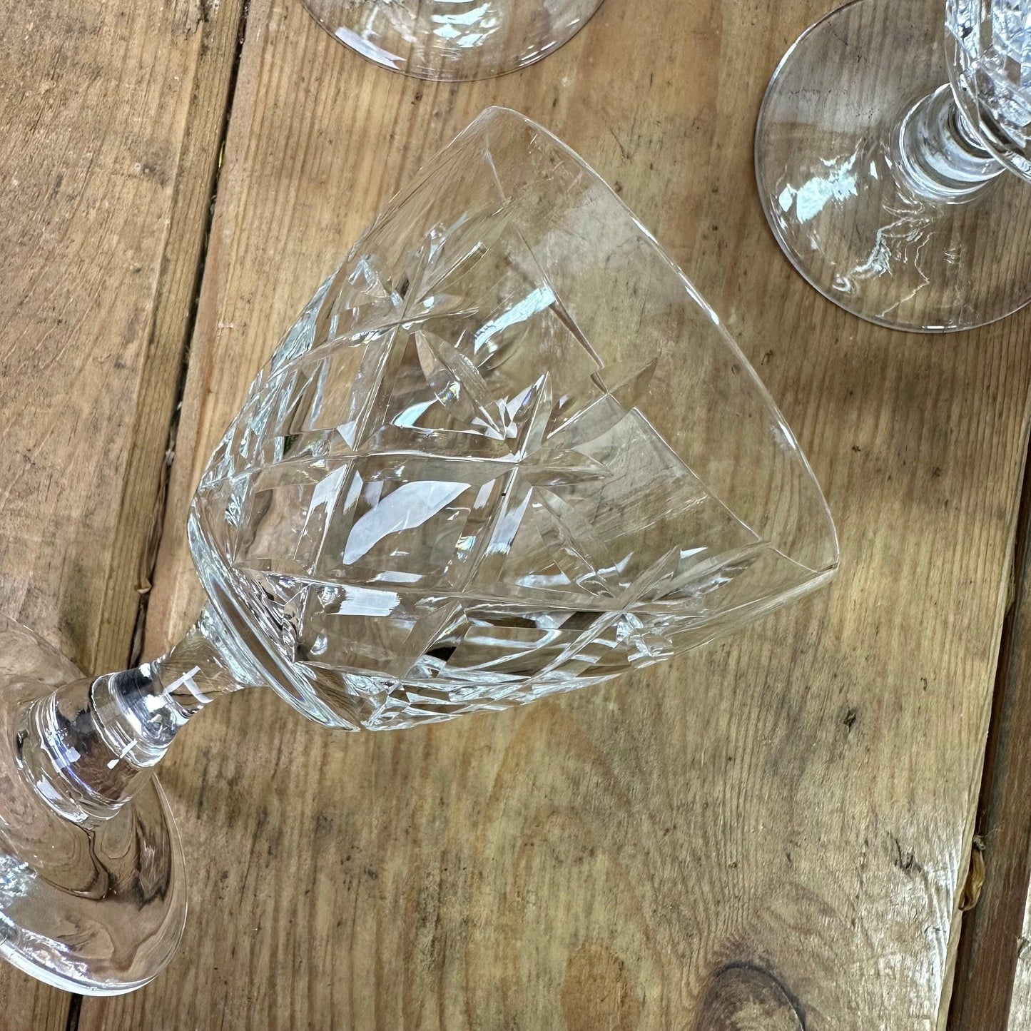 Close-up of a cut crystal wine glass on a wooden table with another glass partially visible